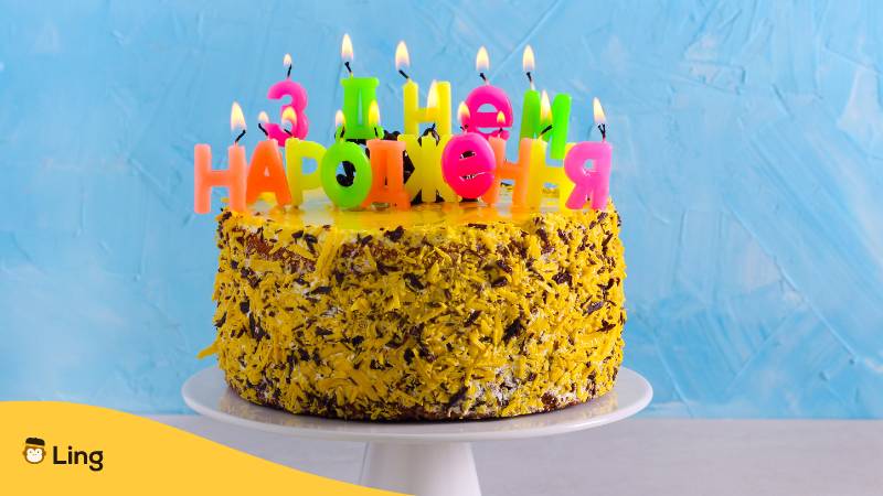 Geburtstagstorte mit Kerzen auf denen нем народженн Alles Gute zum Geburtstag auf Ukrainisch steht
