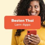 Frau mit Handy an freut sich darüber, die besten Apps um Thai zu lernen gefunden zu haben