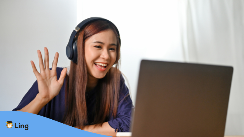 Vietnamesin winkt zur Begrüßung in den Laptop