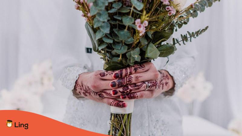 Braut in weißem Brautkleid mit Brautstrauß und Hände bemalt mit Henna ist eine bosnische Hochzeitstradition