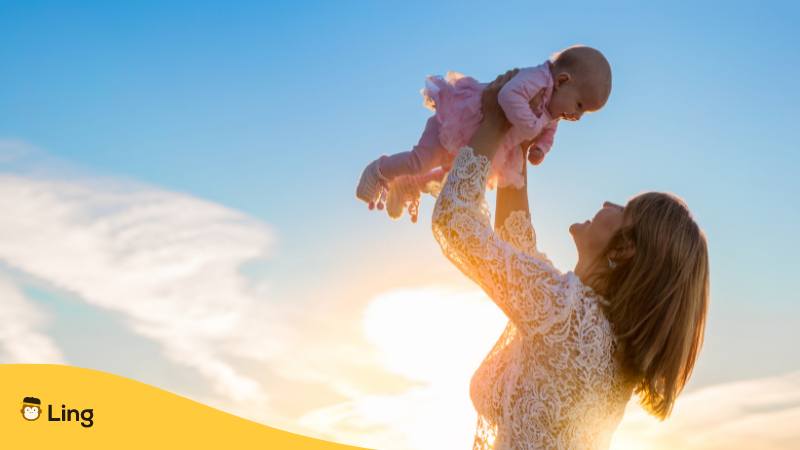 Bosnische Frau hält ihr Baby in die Luft, das einen bosnischen Mädchennamen hat