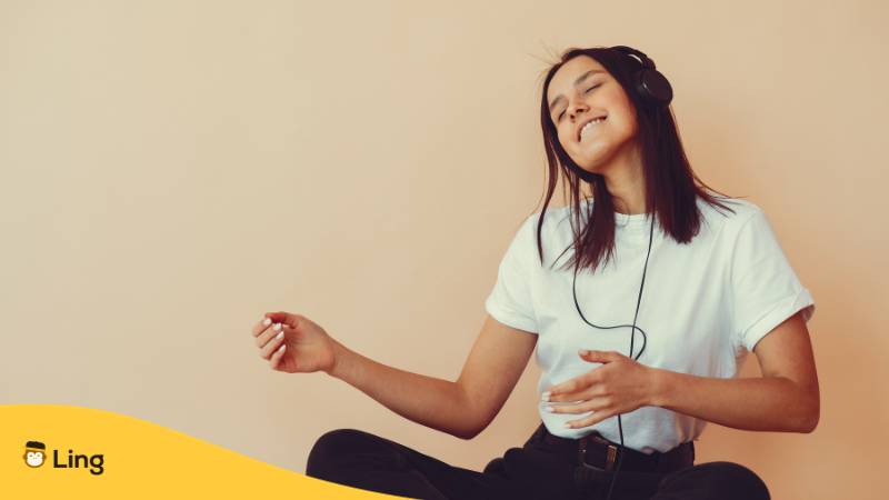 Brünette Frau hat Kopfhörer auf und jammt zur dänischen Musik um mit ihr Dänisch zu lernen