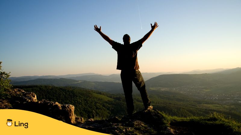 Mann auf einem Berg in Albanien ist dankbar und streckt Arme in die Luft