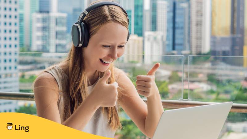 Blonde Frau sitzt vor Laptop und gibt Daumen hoch in die Kamera und freut sich, dass sie schnell Estnisch mit der Ling-App lernen kann, nach dem sie erfahren hat, wie lange dauert es, Estnisch zu lernen?