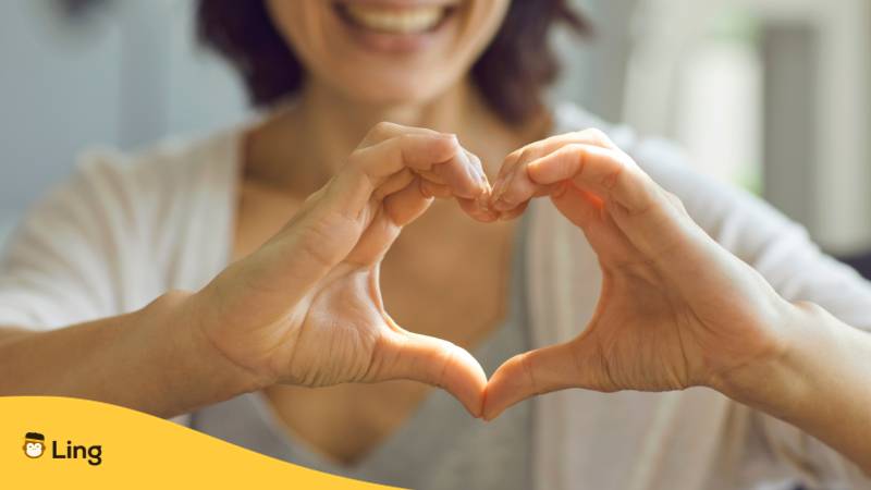 Brünette Frau macht ein Herz mit ihren beiden Händen, weil sie Danke auf Italienisch mit der Ling-App gelernt