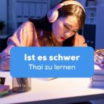 Frau sitzt am Schreibtisch mit Kopfhörern und frägt sich ob schwer Thai zu lernen ist