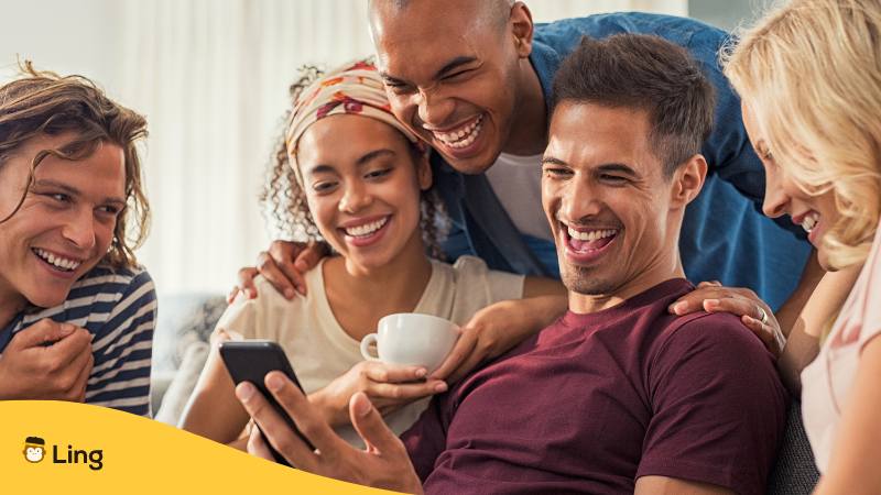 5 Freunde sitzen gemeinsam auf dem Sofa und schauen auf ein Handy und lachen über bosnische Witze
