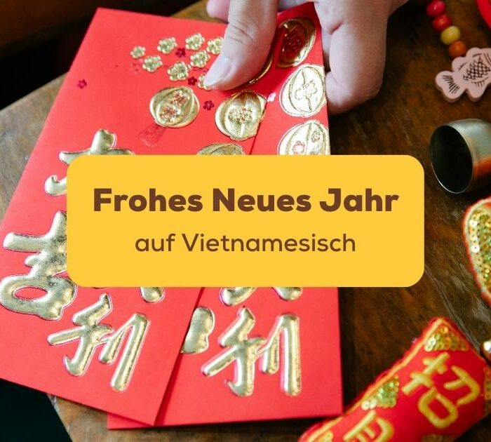 Hand hält rote Umschläge in der Hand um Frohes neues Jahr auf Vietnamesisch zu wünschen