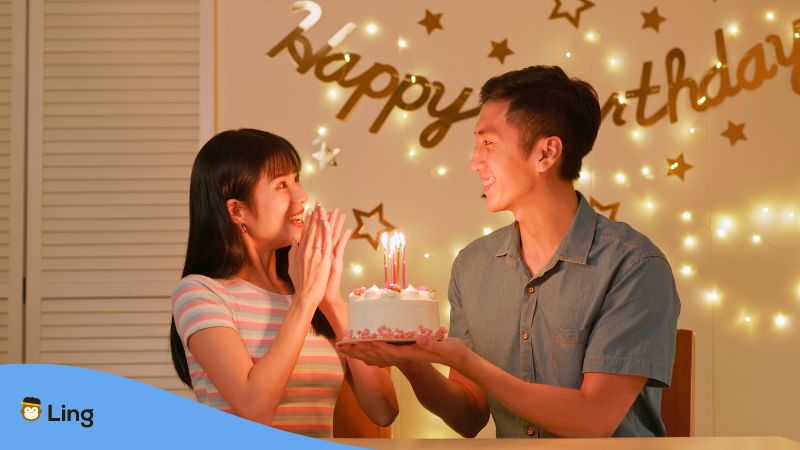 Japanischer Mann hält eine Geburtstagstorte für seine Freundin und möchte ihr Alles Gute zum Geburtstag auf Japanisch wünschen