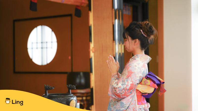 Ein Mädchen aus Japan in festlicher Kleidung, die Handflächen vor der Brust in Kontakt