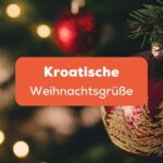 Rote Weihnachtskugeln mit Glitzerdekoration, die an einem grünen Tannenzweig hängen, Kroatische Weihnachtsgrüße