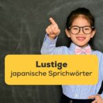 Ein japanisches Mädchen steht vor einer Tafel und macht lachend eine Zeigegeste