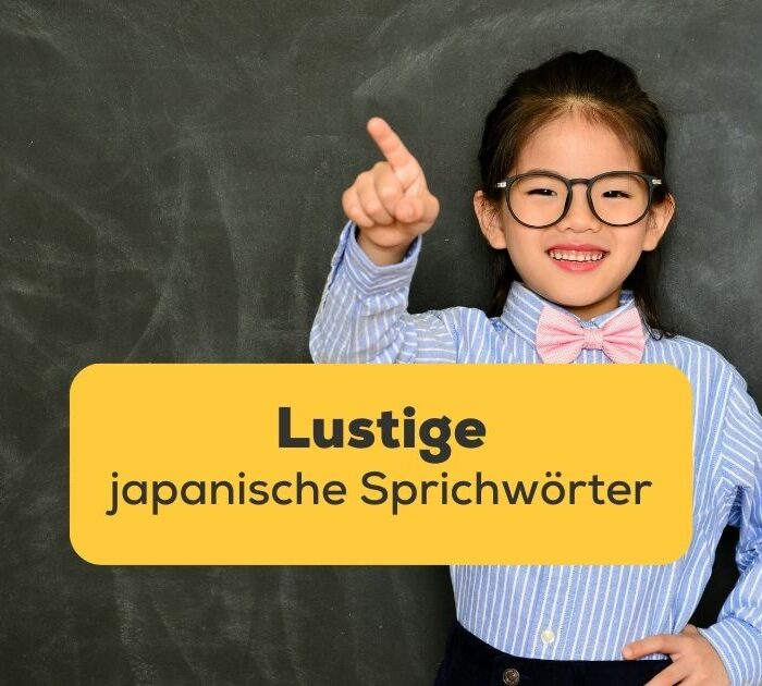 Ein japanisches Mädchen steht vor einer Tafel und macht lachend eine Zeigegeste
