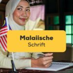Frau in Malaysia sitzt an einem Schreibtisch mit einer malaysischen Flagge und schreibt die malaiische Schrift
