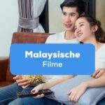 Paar sitzt auf dem Sofa und schaut gemeinsam malaysische Filme an