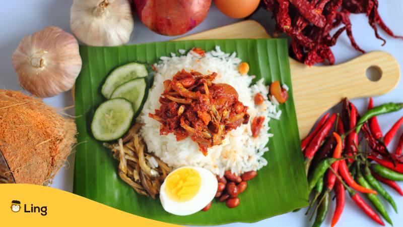 Holzbrett mit einem Bananenblatt auf dem das Gericht Nasi Lemak ist, dem berühmten malaysischen Reisgericht