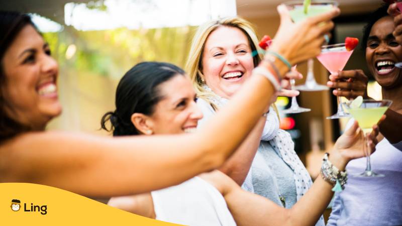 Freundinnengruppe stoßt zusammen mit Cocktails an und sagt Prost auf Französisch