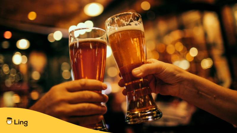 Zwei Biergläser werden angestoßen und dabei Prost auf Lettisch gesagt in einer Kneipe
