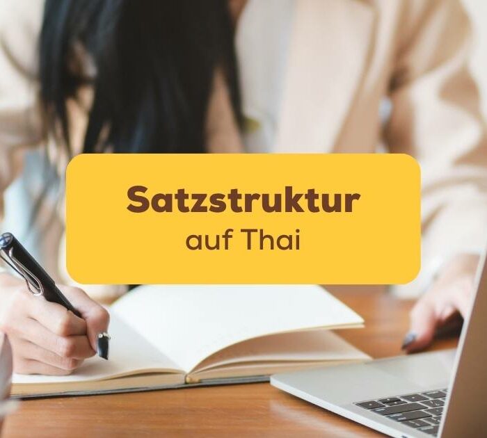 Frau sitzt am Schreibtisch und schreibt in ihr Notizbuch während sie die Satzstruktur auf Thai lernt mit der Ling-App