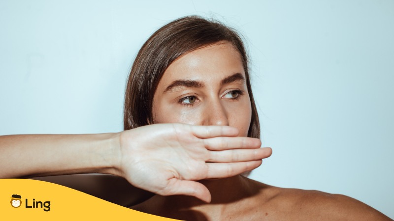 Serbische Frau hält sich den Mund mit der Hand zu um nicht über ein bestimmtes Thema zu sprechen