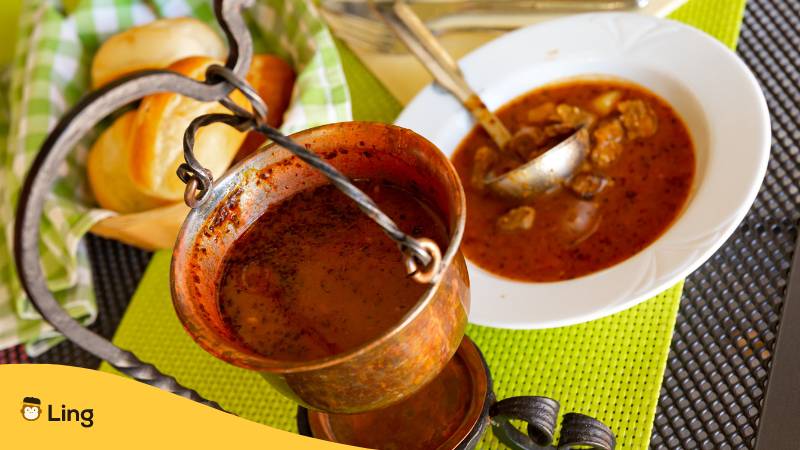 Tisch mit Kupfertopf und Teller in dem Bograc ein slowenischer Eintopf ist