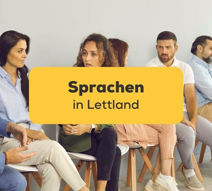 Menschen sitzen auf Stühlen an der Wand und unterhalten sich über die Sprachen in Lettland