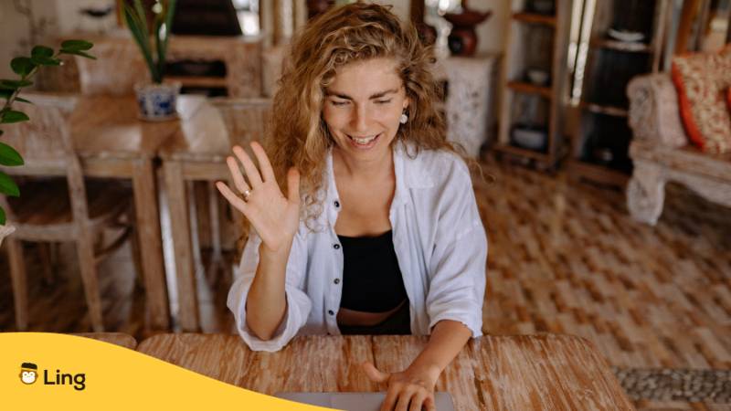 Blonde Frau sitzt am Laptop und kann Ukrainisch mit der Ling-App am Handy oder am Desktop lernen